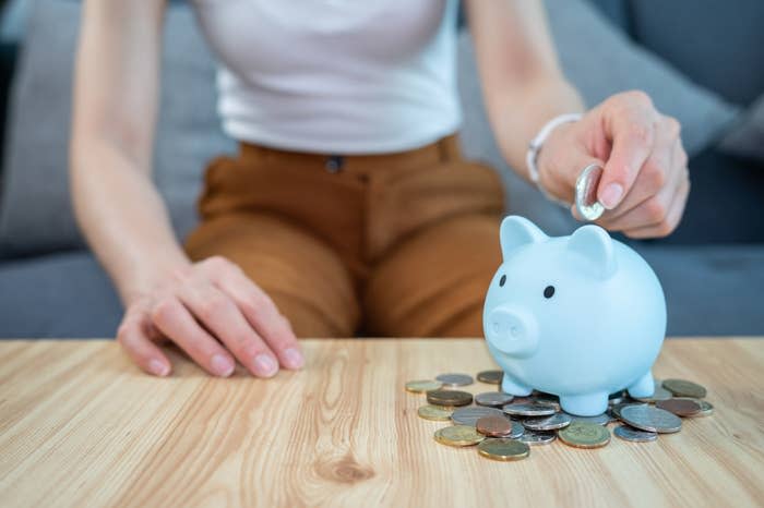 hand putting coins in a piggy bank