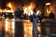 Un joven graba con su teléfono móvil mientras varios coches arden tras una manifestación en Seattle el 30 de mayo. (Foto: Jason Redmond / AFP / Getty Images).