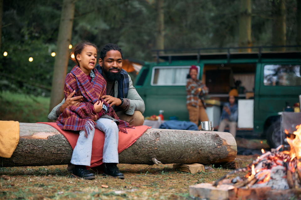 daughter and father sitting next to camp fire