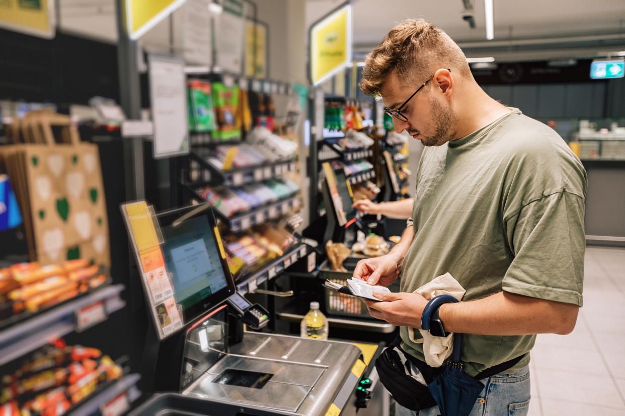 Shopper looks for credit card at a contactless payment in the supermarket. (Credit: Getty Images).