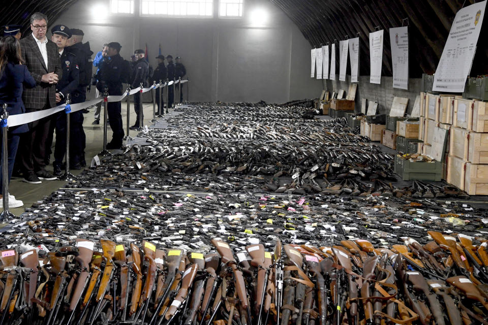 In this photo provided by the Serbian Presidential Press Service, Serbian President Aleksandar Vucic, left, inspects weapons collected as part of an amnesty near the city of Smederevo, Serbia, Sunday, May 14, 2023. (Serbian Presidential Press Service via AP)