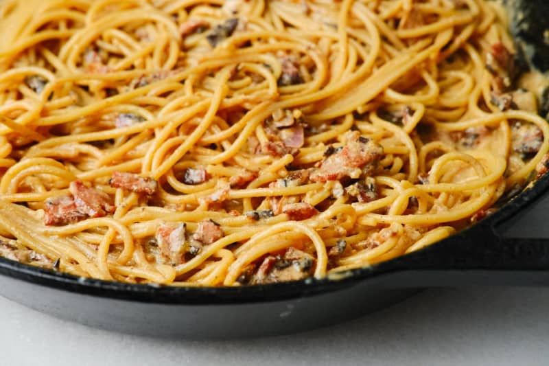 Spaghetti noodles with bacon bits and shredded cheese