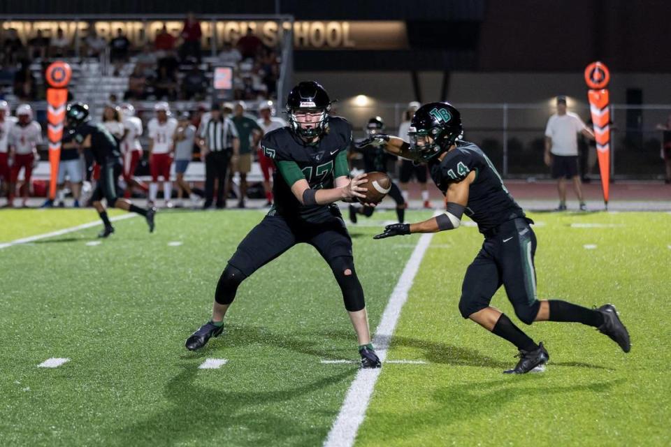 Twelve Bridges quarterback Whit Kruse (17) hands off the ball to running back Nathan Crawford (14) during the fourth quarter in the game Friday, Aug. 19, 2022, at Twelve Bridges High School in Lincoln. The Raging Rhinos defeated the Lions 36-35.