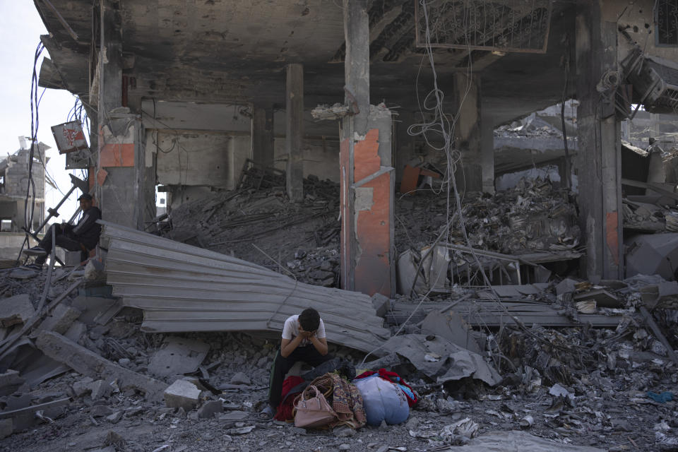 Palestinians sit on the destruction in the wake of an Israeli air and ground offensive in Khan Younis, southern Gaza Strip, Monday, April 8, 2024. Israel says it has withdrawn its last ground troops from the city, ending a four-month operation. (AP Photo/Fatima Shbair)