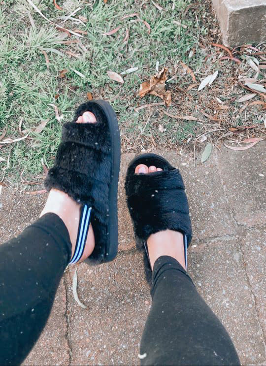 A woman's feet wearing Kmart's $12 black furry slippers