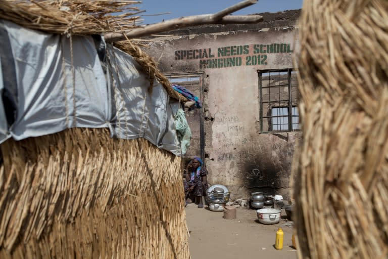 A girl sits beside cooking utensils near a school burnt in a camp for internally displaced people at Monguno district of Borno State on February 14, 2017