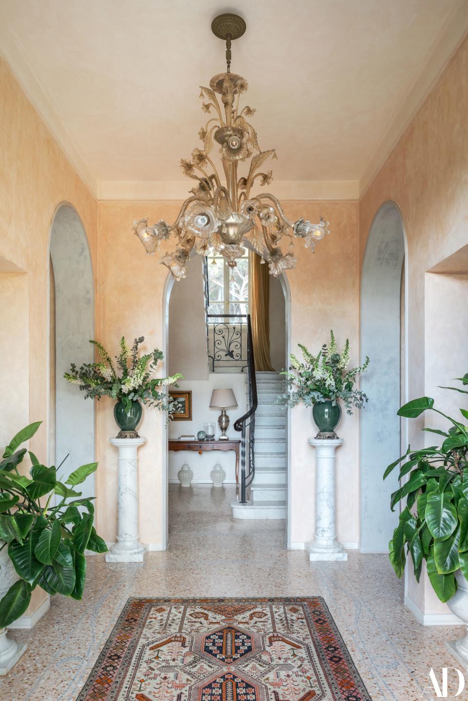 The foyer of Andrea Bocelli's home on Italy’s Tuscan coast overflows with greenery. The rug is an heirloom from Bocelli’s mother’s home, and the chandelier is from “Private Collection” by Anita Majoli.