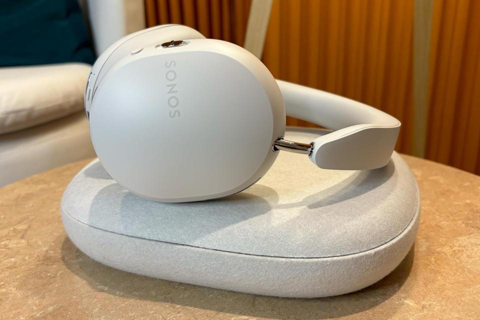 <p>White headphones laying on a white cloth case on a small table.</p>
