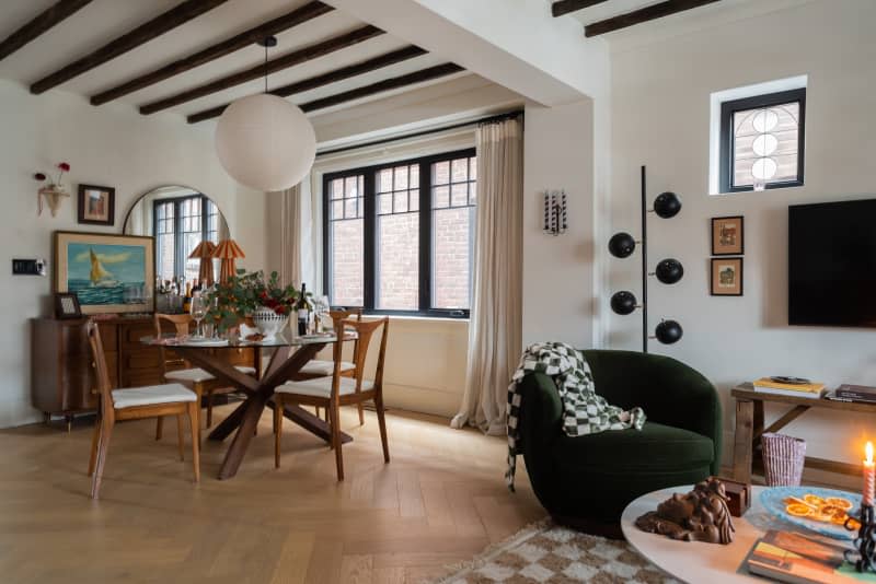 Living room and dining room area of a large home with wooden floors and black accents.