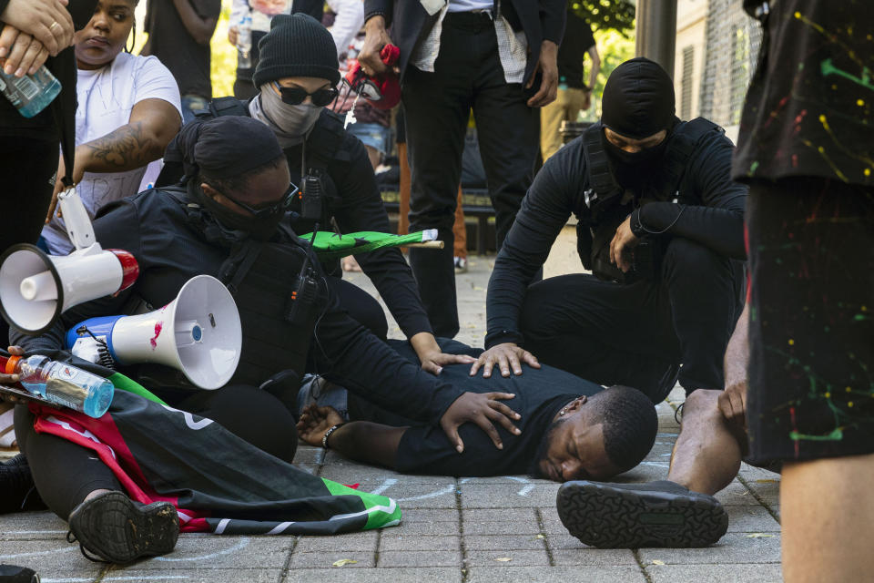 Jimmy Barwan, cousin of Patrick Lyoya is comforted by protesters during a moment of silence outside Grand Rapids Police Department in Grand Rapids, Mich. on Thursday, June 9, 2022. A prosecutor filed a second-degree murder charge Thursday against the Michigan police officer who killed Patrick Lyoya, a Black man who was on the ground when he was shot in the back of the head following an intense physical struggle recorded on a bystander's phone. (Joel Bissell/The Grand Rapids Press via AP)