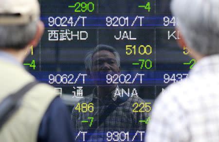 A man is reflected on an electronic stock quotation board outside a brokerage in Tokyo May 16, 2014. REUTERS/Yuya Shino