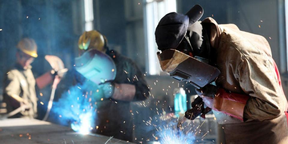 A worker cutting steel at a factory