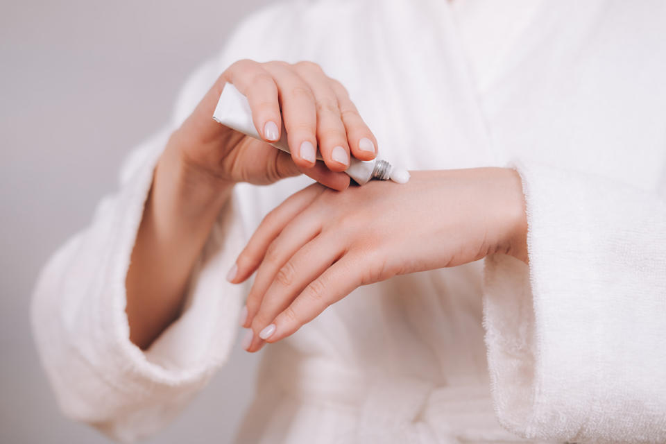 Woman applying moisturizer on hands.