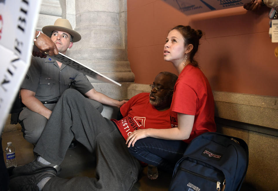 A protester who became unresponsive while being arrested by state police is helped by medical personnel as tenants and members of the Upstate Downstate Housing Alliance from across the state demand New York Gov. Andrew Cuomo and state legislators pass universal rent control legislation that would strengthen and expand tenants rights across the state of New York before rent laws expire on June 15, during a protest rally at the state Capitol Tuesday, June 4, 2019, in Albany, N.Y. (AP Photo/Hans Pennink)\