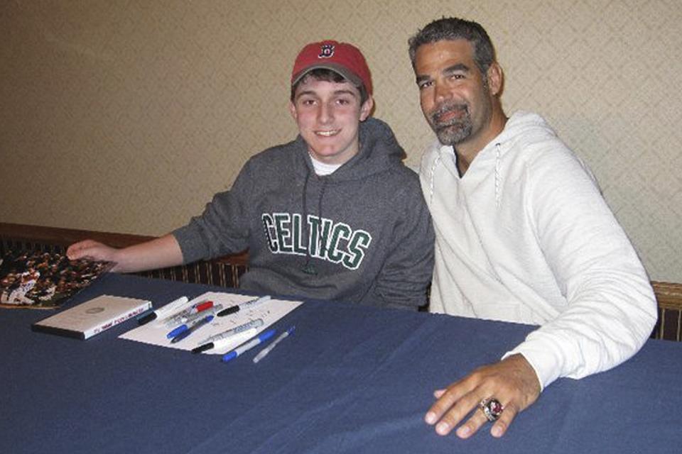 In this 2011 photo provided by David Cotillo, his son Chris Cotillo, left, poses with former Boston Red Sox third baseman Mike Lowell during an autograph session in Boston. Chris Cotillo, a Red Sox beat writer for MassLive.com in 2020, raised tens of thousands of dollars by selling autographed baseball memorabilia he had collected as a teen and that others donated for the auction. (David Cotillo via AP)