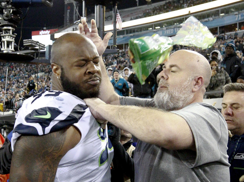 A Seahawks staff member tries to remove Seahawks defensive tackle Quinton Jefferson, left, from the field as an object thrown from the stands hits them during the closing moments of Sunday's game. (AP) 