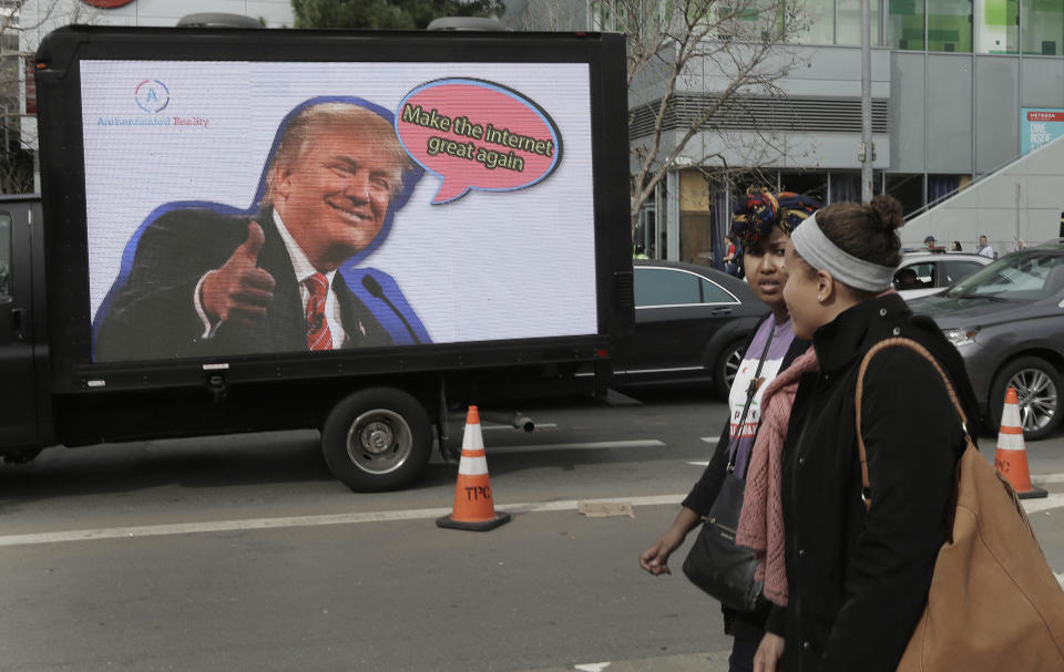 In this Monday, Feb. 13, 2017 photo, protesting tech workers walk past a mobile billboard of Donald Trump in San Francisco. In the wake of the 2016 election, old-school, anti-capitalist activists and new-school, free-enterprise techies in the city are pushing aside their differences to take on a common foe. (AP Photo/Ben Margot)