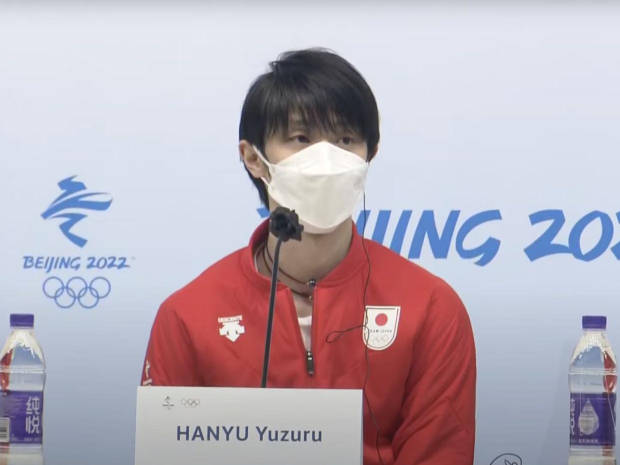 A snapshot of Japanese figure skater Yuzuru Hanyu in a red Team Japan jacket at a news conference in Beijing, February 2022.
