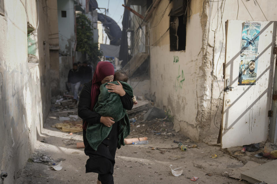 Palestinians walk by a damaged building following an Israeli army operation in Jenin refugee camp, West Bank, Sunday, Nov. 26, 2023. Israeli forces operating in the occupied West Bank killed at least eight Palestinians in a 24-hour period, Palestinian health officials said Sunday. (AP Photo/Majdi Mohammed)