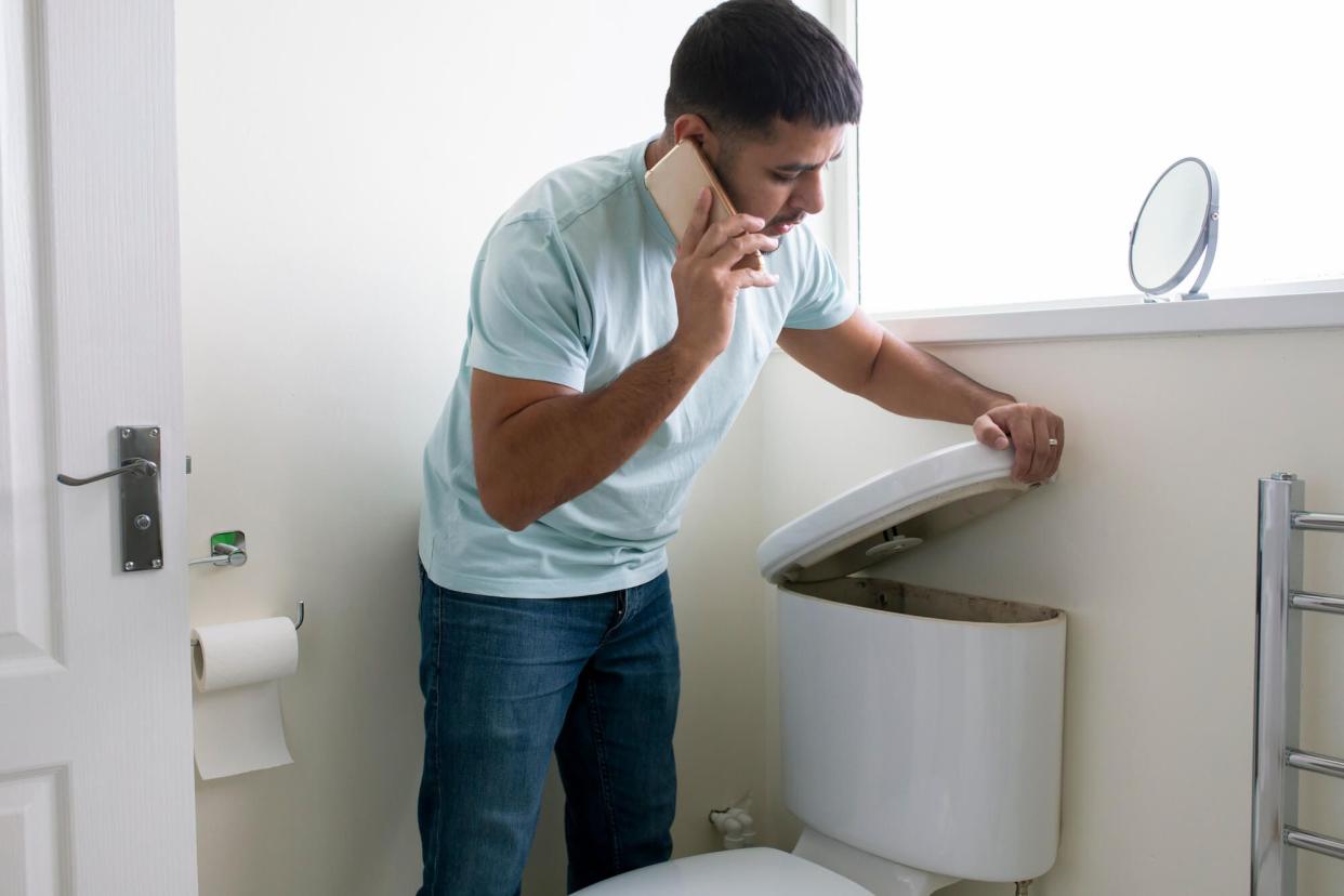 Man looking at broken toilet