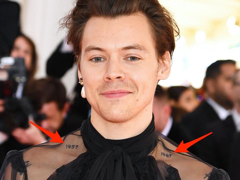 Red arrows pointing to tattoos on Harry Styles' shoulders.