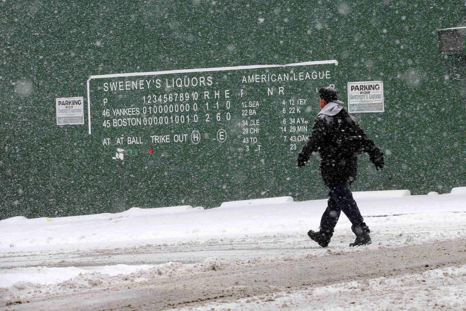 A pedestrian walks past a replica of the Fenway Park scoreboard during a winter nor'easter snow storm in Lawrence