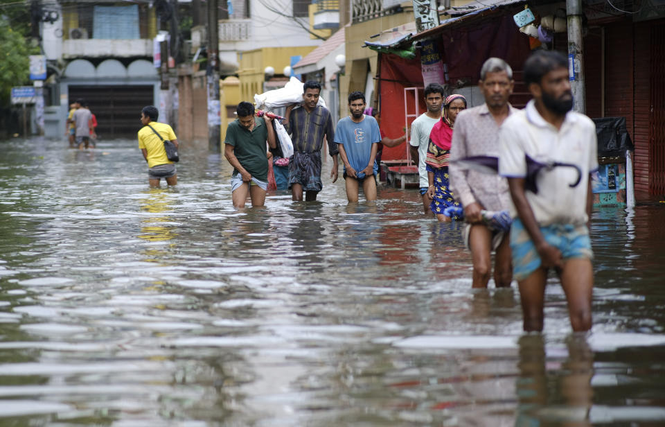 People wade through flood waters in Sylhet, Bangladesh, Monday, June 20, 2022. Floods in Bangladesh continued to wreak havoc Monday with authorities struggling to ferry drinking water and dry food to flood shelters across the country’s vast northern and northeastern regions. (AP Photo/Mahmud Hossain Opu)