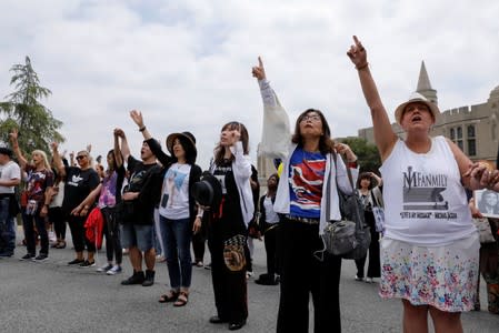 Fans point to the sky after a moment of silence at Forest Lawn Cemetery ten years after the death of child star turned King of Pop, Michael Jackson, in Glendale, California