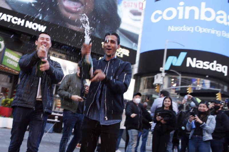 Employees and supporters of Coinbase pop the corks on bottles of champagne at the NASDAQ MarketSite where the Coinbase logo is displayed on screens in Times Square when Coinbase Global beings trading under the symbol COIN on April 14, 2021. File Photo by John Angelillo/UPI