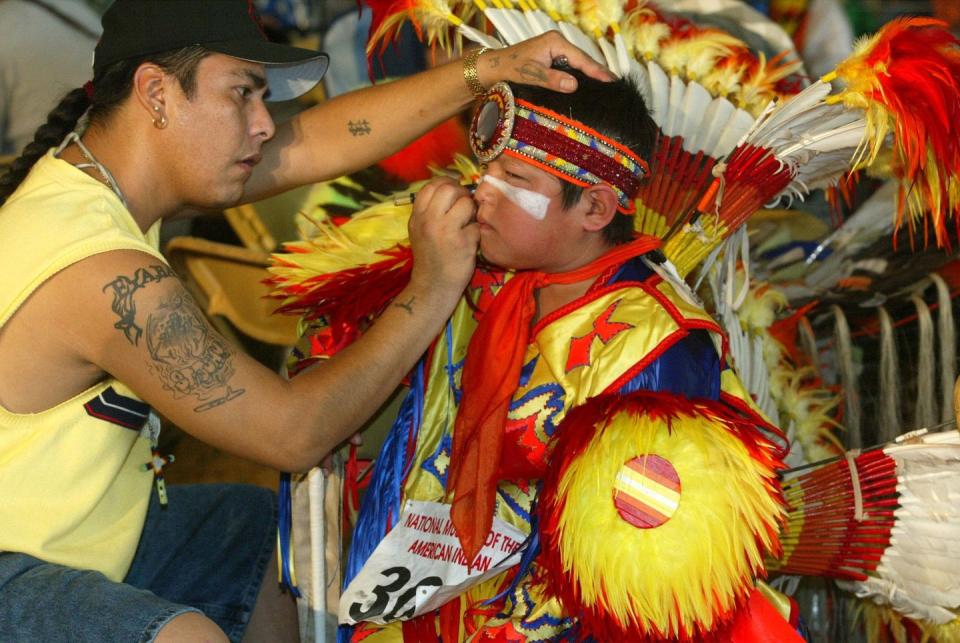 terry st john, of dakota tribe of minnesota, puts make up on the face of rick cleveland, jr, of ho chunk tribe of wisconsin, during the smithsonian's pow wow marking the continuing construction of the national museum of the american indian