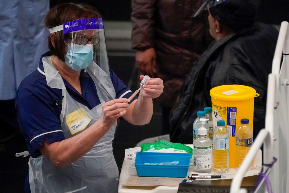 A health worker holds a vaccine as she prepares to administer it. 