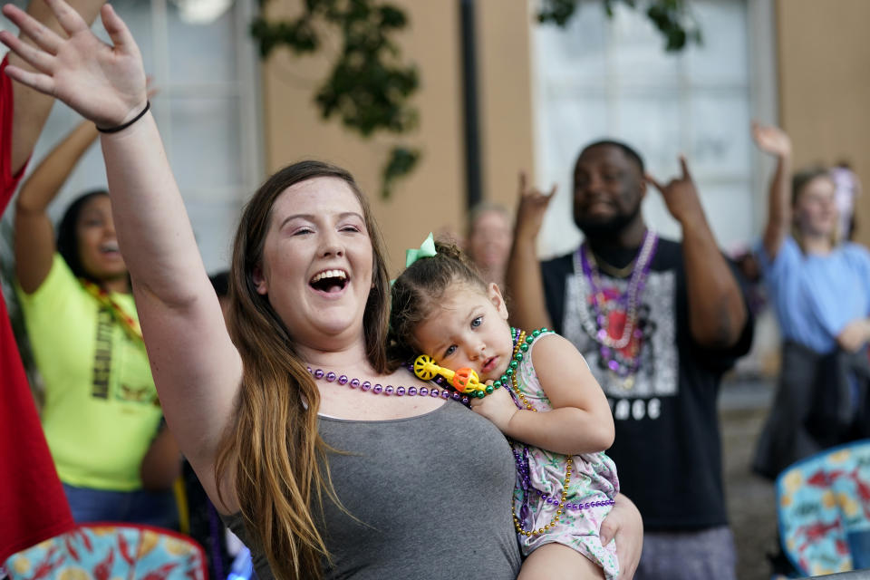 Hayley Bosarge vies for throws as she holds her daughter Ellie Bosarge, 2, during a parade dubbed "Tardy Gras," to compensate for a cancelled Mardi Gras due to the COVID-19 pandemic, in Mobile, Ala., Friday, May 21, 2021. (AP Photo/Gerald Herbert)