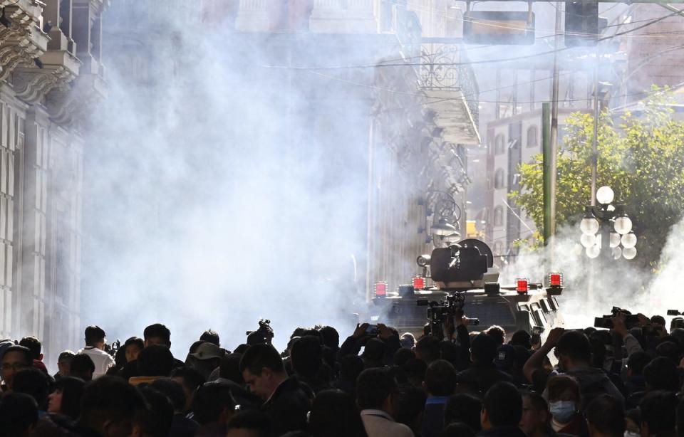 Military troops in armoured vehicles fire teargas at crowds outside the Quemado Palace at Plaza Murillo in La Paz (AFP via Getty)