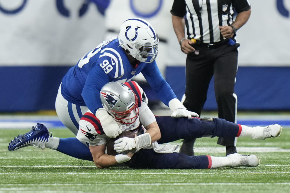 New England Patriots quarterback Mac Jones, bottom, slides with the ball as he is stopped by Indianapolis Colts defensive tackle DeForest Buckner (99) during the first half of an NFL football game Saturday, Dec. 18, 2021, in Indianapolis. (AP Photo/AJ Mast)