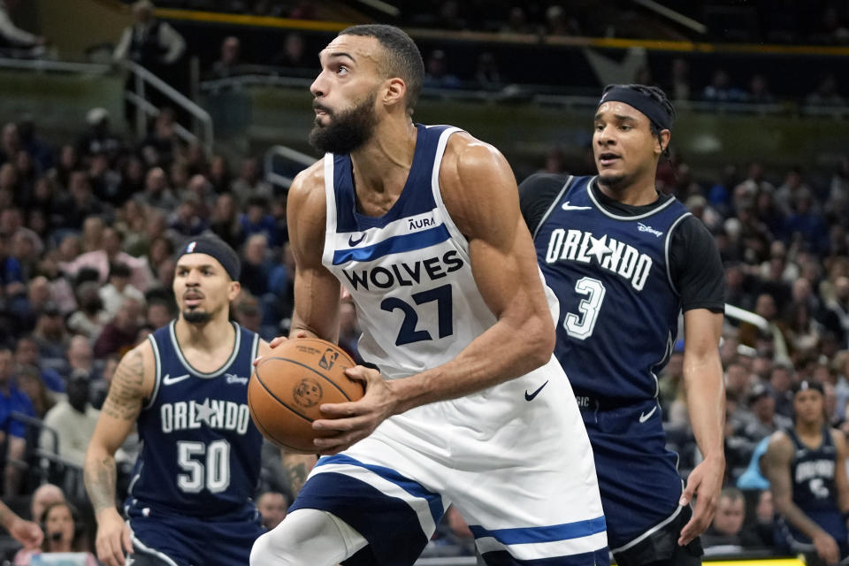 Minnesota Timberwolves center Rudy Gobert (27) goes past Orlando Magic guard Cole Anthony (50) and forward Chuma Okeke (3) as he looks for a shot during the first half of an NBA basketball game, Tuesday, Jan. 9, 2024, in Orlando, Fla. (AP Photo/John Raoux)