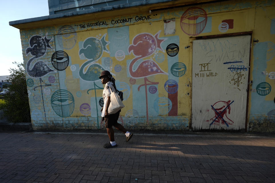 A person walks past an empty building, which housed the once popular entertainment spot the Tiki Club, in the Miami neighborhood of west Coconut Grove, Friday, April 5, 2024. Historically Black West Coconut Grove is a majority Black neighborhood hidden among some of the most affluent areas in Miami that once boomed with sports and economics. (AP Photo/Lynne Sladky)