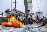 Crew from the United States' American Magic boat Patriot and Team New Zealand attempt to keep Patriot afloat after it capsized during its race against Italy's Luna Rossa on the third day of racing of the America's Cup challenger series on Auckland's Waitemate Harbour, New Zealand, Sunday, Jan. 17, 2021. (Michael Craig/NZ Herald via AP)