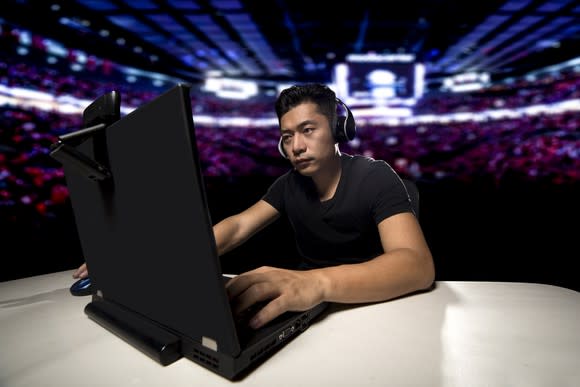 Young man wearing headphones and typing on a laptop.