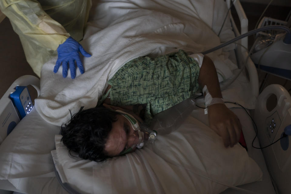 Registered nurse Nvard Termendzhyan helps Julio Valladares, 46, change his position while treating him in a COVID-19 unit at Providence Holy Cross Medical Center in Los Angeles, Monday, Dec. 13, 2021. At the medical center, just 17 coronavirus patients were being treated there Friday, a small fraction of the hospital's worst stretch. Nurse manager Edgar Ramirez said his co-workers are weary but better prepared if a wave hits. (AP Photo/Jae C. Hong)