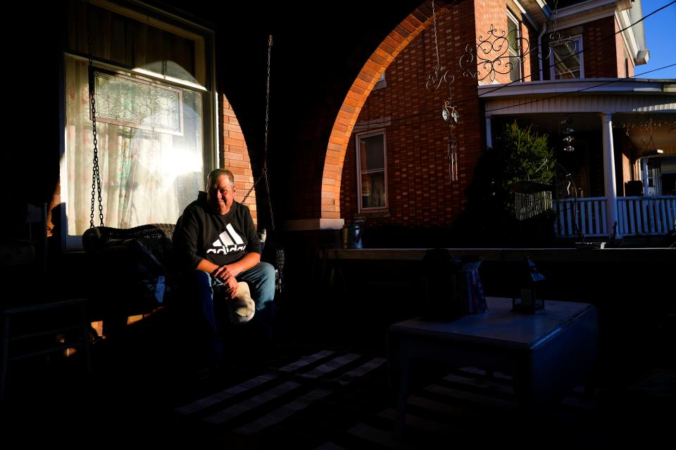 Chris Sechrest sits on his porch swing in the bright evening light on Nov. 13 at his home in Aurora, Ind.