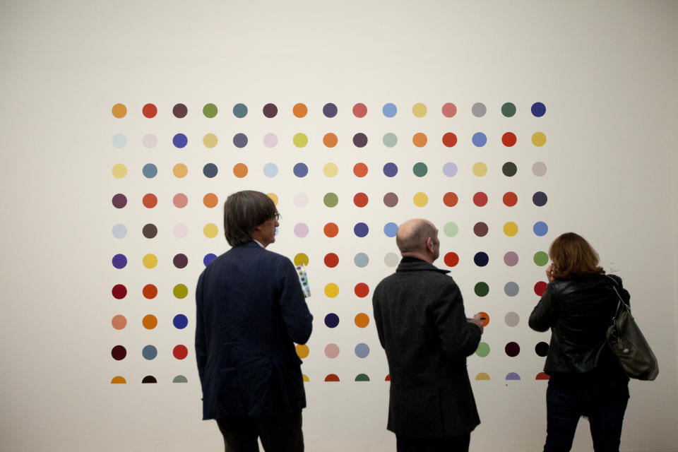 People look at British artist Damien Hirst's 1986 piece "Spot Painting", household gloss on board, during a media preview of the first substantial show of his work in the UK at the Tate Modern gallery in London, Monday, April 2, 2012.  The exhibition, timed for the culmination of the Cultural Olympiad and due to open to the public on Wednesday, showcases over 70 of Hirst's works since he first came to public attention in 1988.  (AP Photo/Matt Dunham)