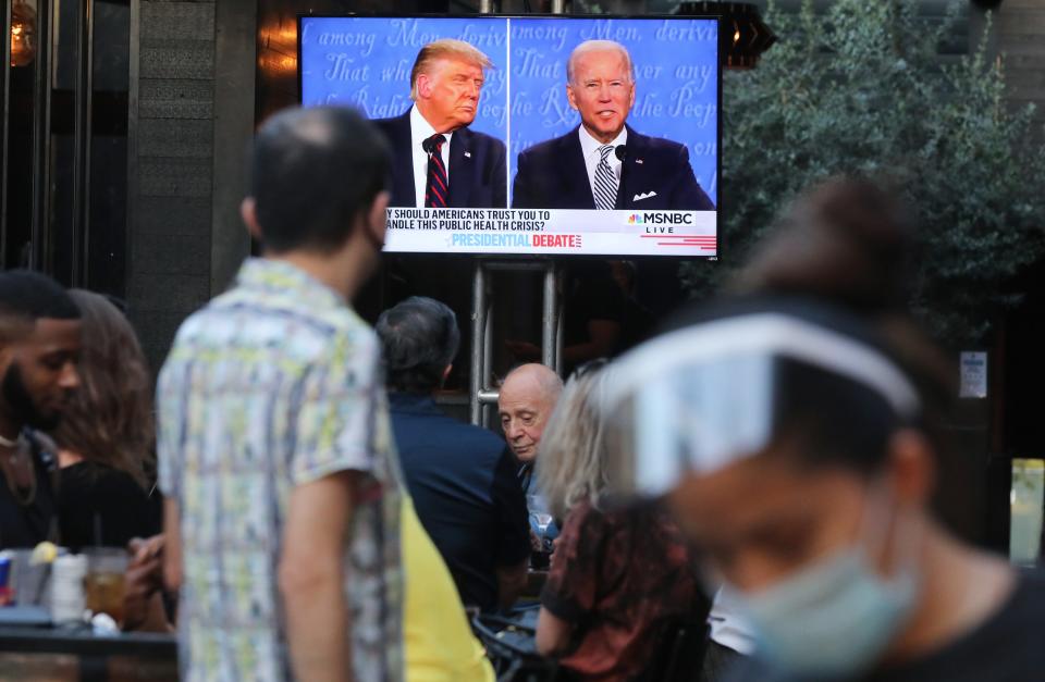 A server wears a face shield and face-covering as people sit to watch a broadcast of the first debate between President Donald Trump and Democratic presidential nominee Joe Biden.