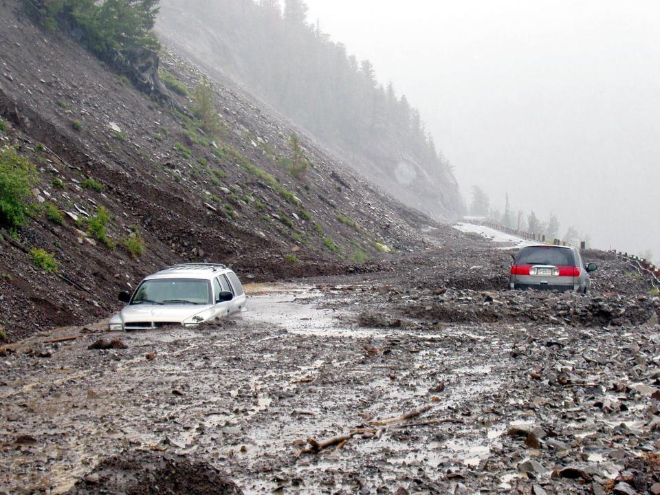 Two cars are trapped in mud July 19, 2004 on the East Entrance Road near Sylvan Pass in Yellowstone National Park in Wyoming. Park rangers rescued 16 people, some through their car windows, after thunderstorms caused the mud to begin flowing July 18.  No injuries were reported.