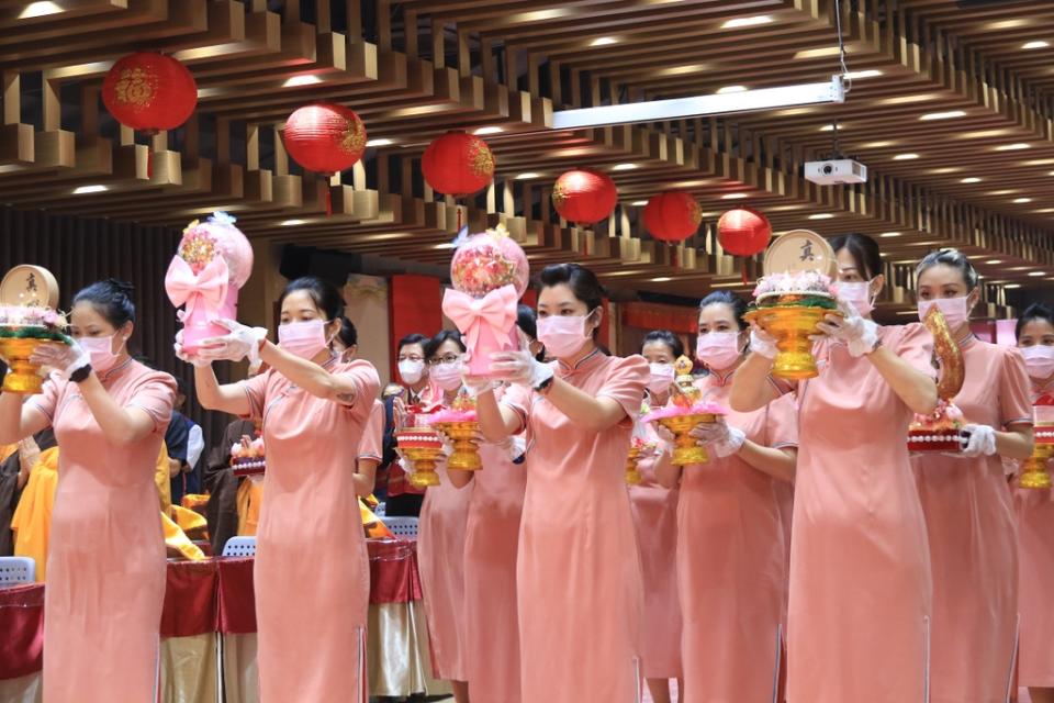 《圖說》「全球獻供」主場隊伍身著粉橘色旗袍，以花、果、燈、經文、寶瓶、海螺、舍利塔等十供養，莊嚴會場。（靈鷲山佛教教團提供）