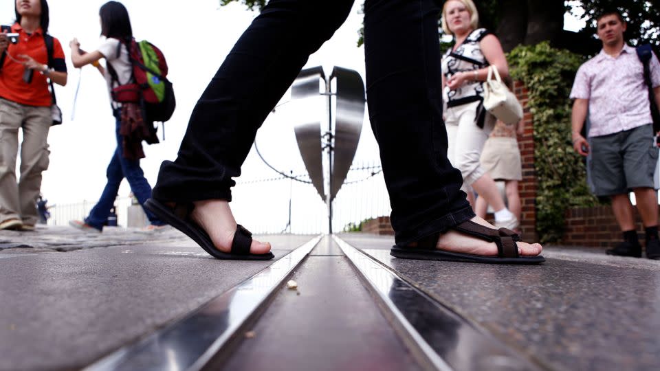 A tourist walks across the Prime Meridian in Greenwich, London. - Newscast/Shutterstock