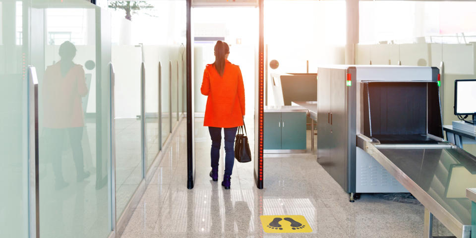 Female passenger walking through the airport security checkpoint.