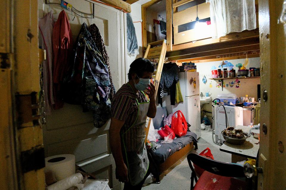 Resident Qin Chan fixes her mask inside of her room in her Chinatown single-room occupancy building, one of many low-income structures that house poor Asian Americans who are at increased risk of COVID-19 as a result of living in tight quarters.