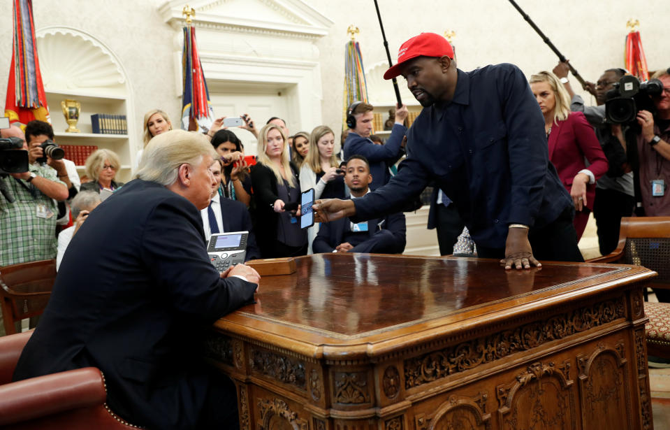 Rapper Kanye West shows President Trump his mobile phone during a meeting in the Oval Office at the White House Thursday. (Photo: Kevin Lamarque/Reuters)