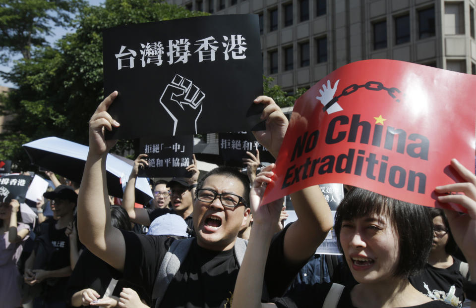 Hong Kong students and Taiwan supporters shout and hold slogans to oppose Hong Kong's proposed extradition law outside the Legislative Yuan in Taipei, Taiwan, Sunday, June 16, 2019. Hong Kong residents Sunday continued their massive protest over an unpopular extradition bill that has highlighted the territory's apprehension about relations with mainland China, a week after the crisis brought as many as 1 million into the streets. (AP Photo/Chiang Ying-ying)