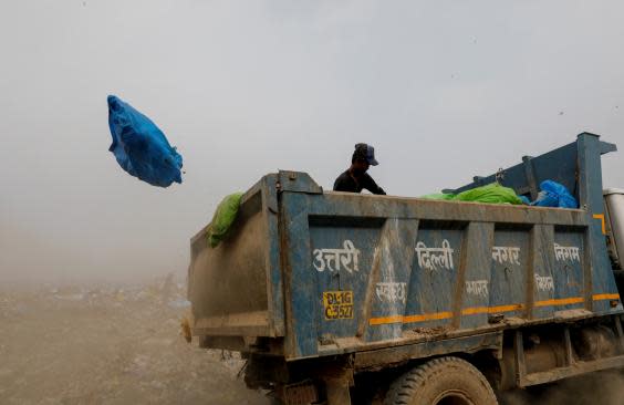 A waste collector goes through bags of rubbish as he throws them off the truck (Reuters)